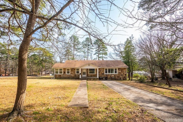 view of front of house featuring a front yard, stone siding, and driveway