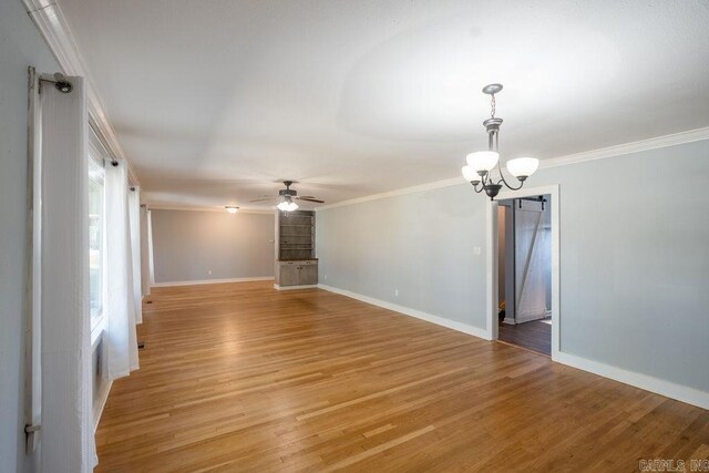 empty room with light wood-style flooring, ceiling fan with notable chandelier, baseboards, and ornamental molding