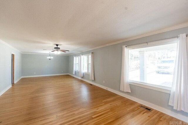 empty room with light wood finished floors, visible vents, crown molding, and ceiling fan