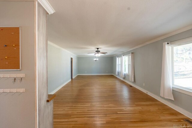 spare room featuring ornamental molding, baseboards, light wood finished floors, and ceiling fan