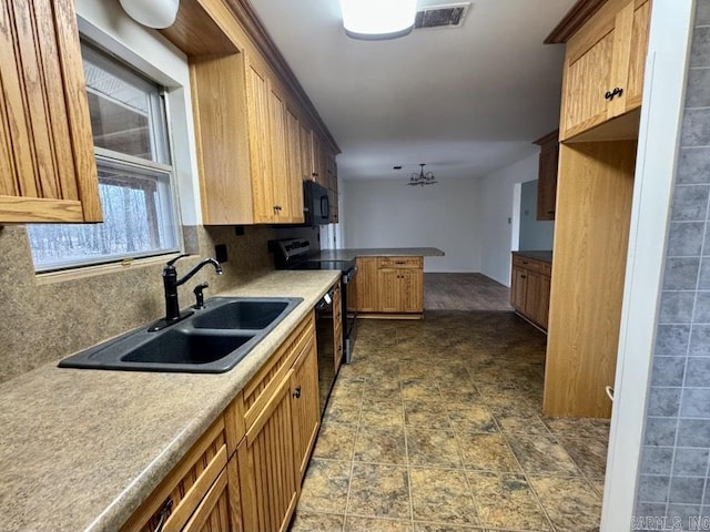 kitchen featuring kitchen peninsula, decorative backsplash, sink, and black appliances