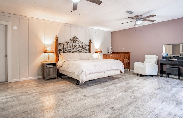 bedroom with ceiling fan, light hardwood / wood-style flooring, and a textured ceiling