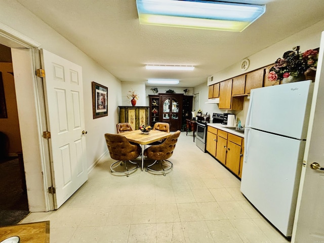 kitchen with electric range, white fridge, and a textured ceiling