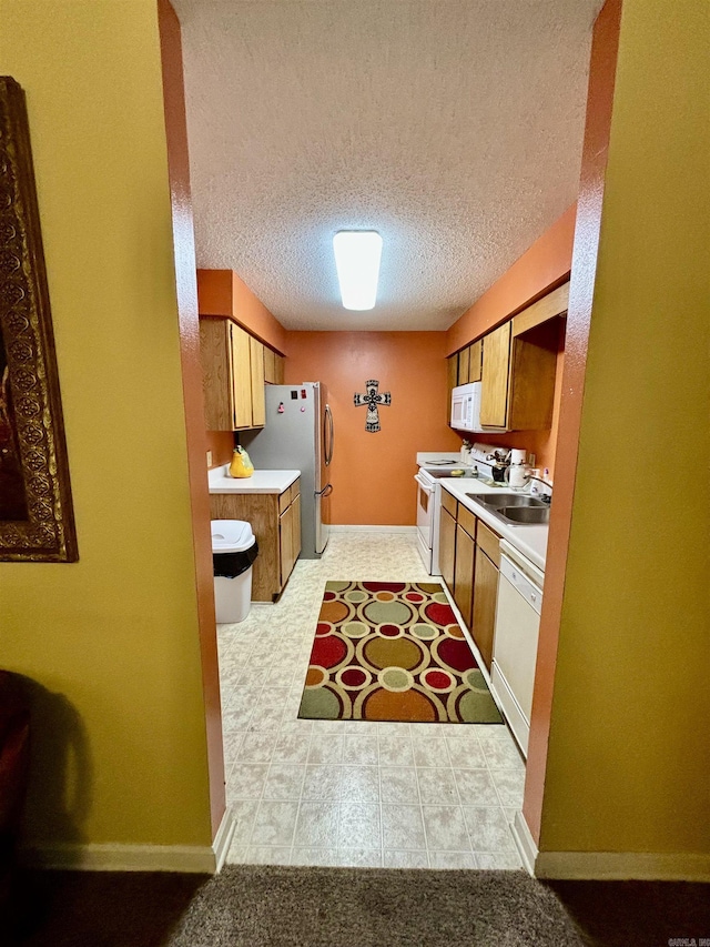 kitchen featuring a textured ceiling, sink, and white appliances