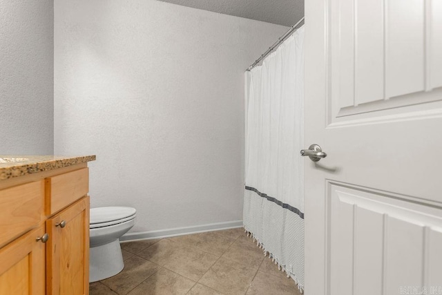 bathroom with tile patterned flooring, vanity, a textured ceiling, and toilet