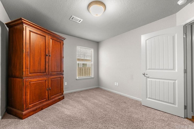 unfurnished bedroom with a textured ceiling and light carpet