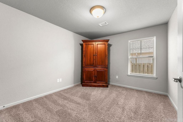 unfurnished room featuring light colored carpet, lofted ceiling, and a textured ceiling