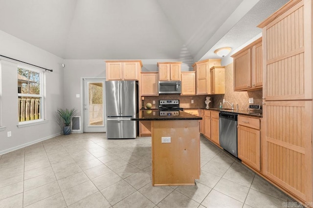 kitchen featuring stainless steel appliances, light brown cabinets, a center island, lofted ceiling, and light tile patterned flooring