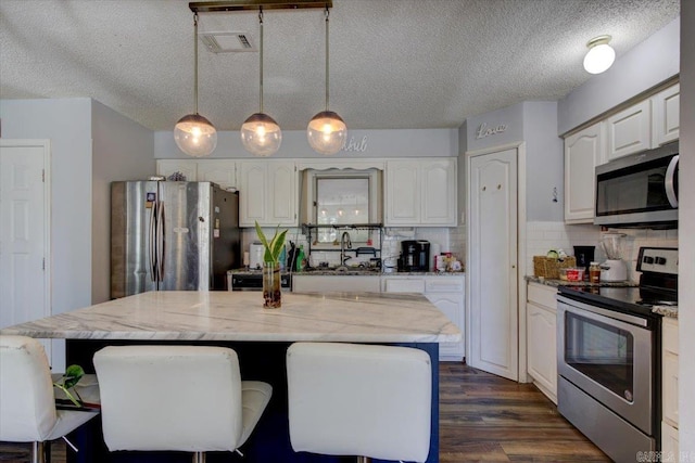 kitchen with sink, pendant lighting, a center island, and stainless steel appliances