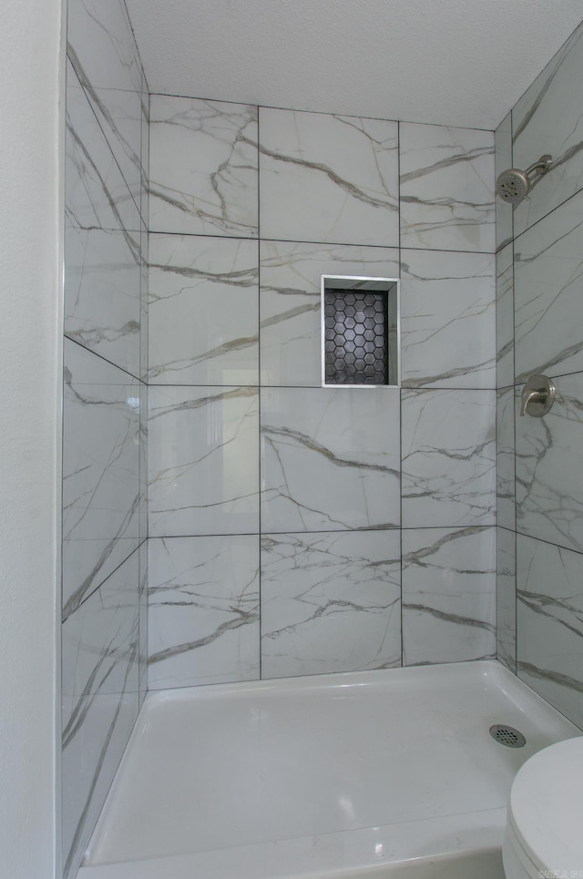 bathroom with tiled shower and toilet