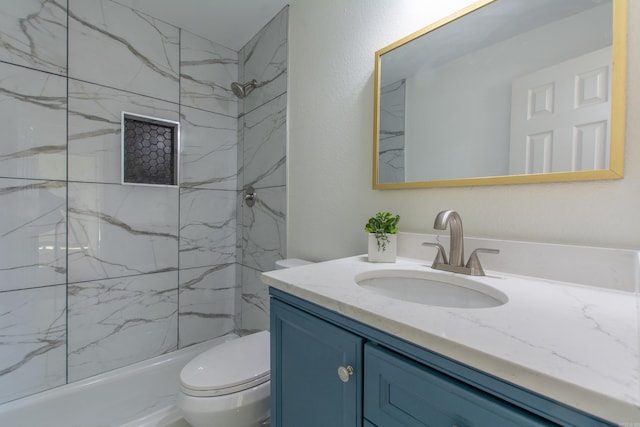 bathroom with a tile shower, vanity, and toilet