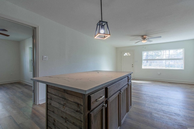 kitchen with dark wood-type flooring, ceiling fan, a center island, and pendant lighting