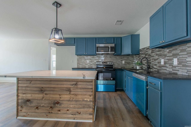 kitchen with pendant lighting, stainless steel appliances, blue cabinets, and sink