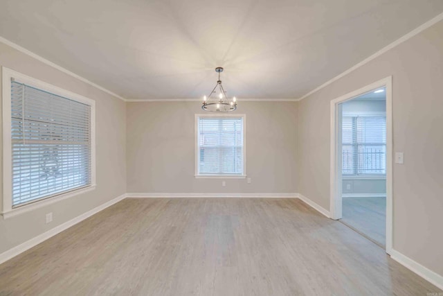 empty room featuring a healthy amount of sunlight, ornamental molding, a chandelier, and light wood-type flooring