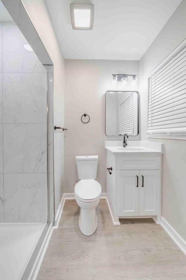 bathroom featuring tiled shower, hardwood / wood-style floors, vanity, and toilet