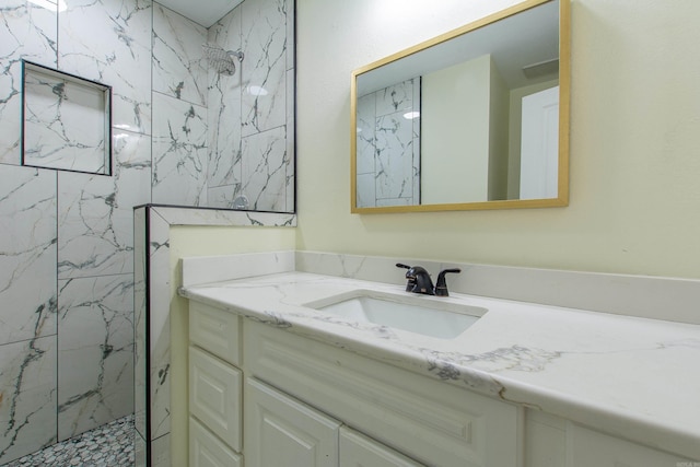 bathroom with a tile shower and vanity