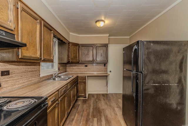 kitchen featuring sink, hardwood / wood-style flooring, ornamental molding, and black appliances