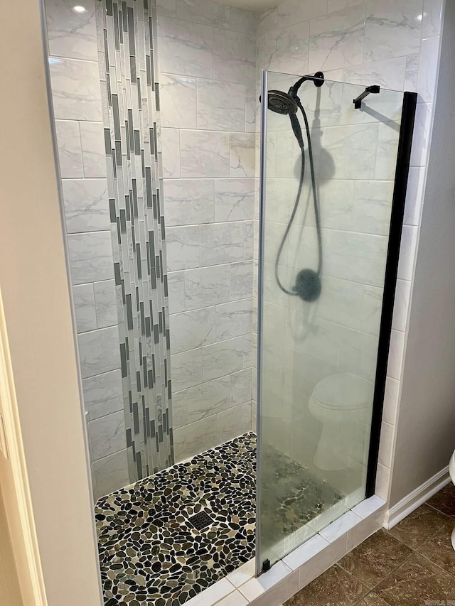 bathroom with a tile shower and toilet