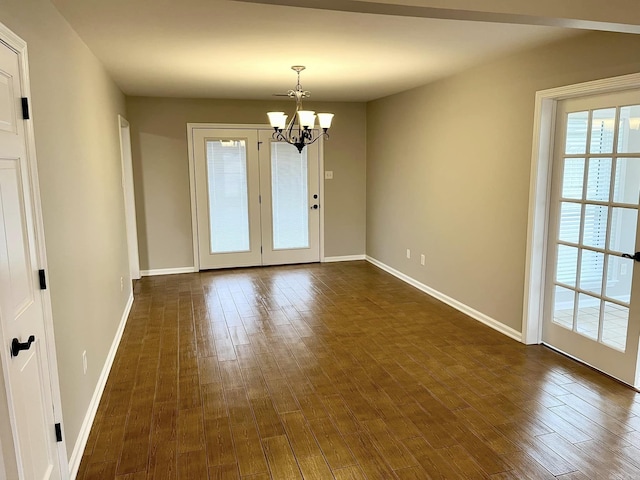 empty room with dark hardwood / wood-style flooring and an inviting chandelier