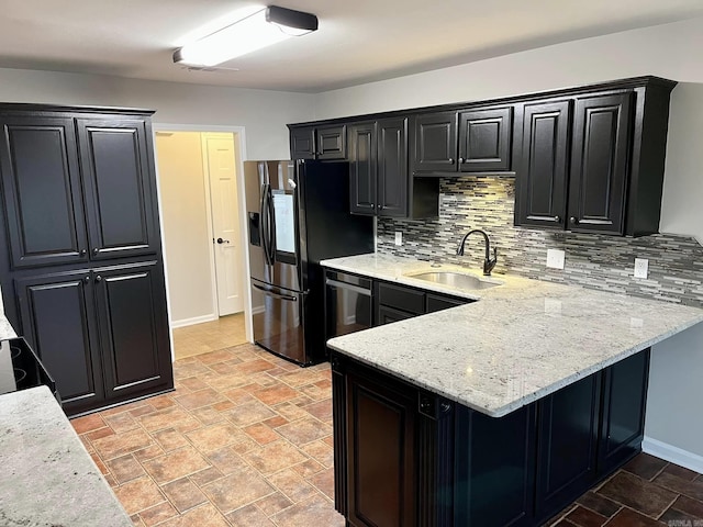 kitchen featuring backsplash, sink, light stone countertops, appliances with stainless steel finishes, and kitchen peninsula