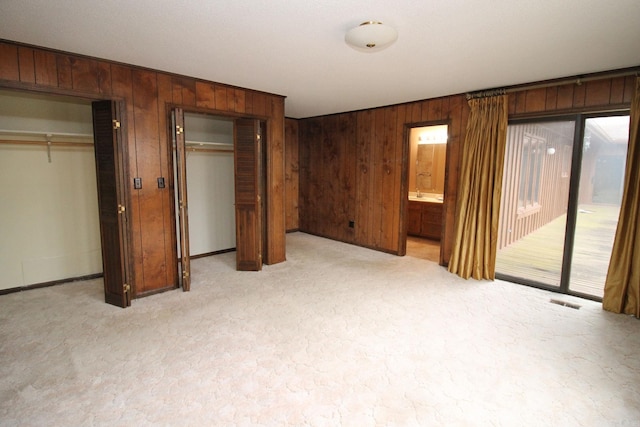 unfurnished bedroom featuring access to exterior and two closets