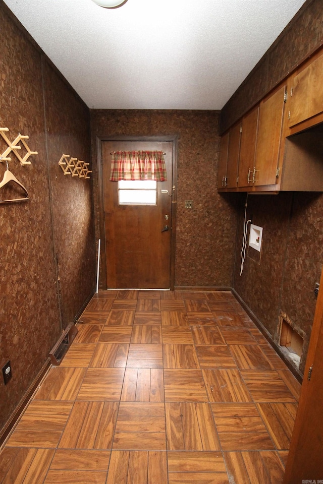 laundry room featuring dark parquet flooring, hookup for a washing machine, cabinets, and a textured ceiling