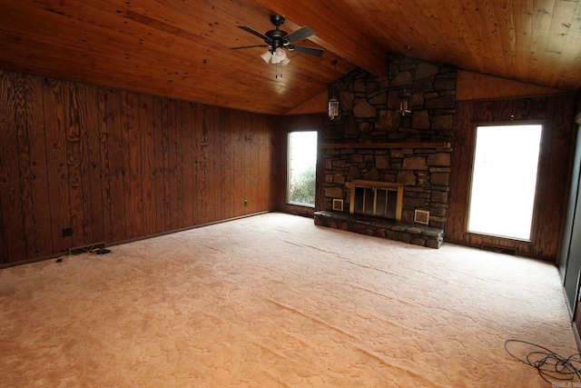 unfurnished living room featuring a stone fireplace, wood walls, ceiling fan, and vaulted ceiling with beams