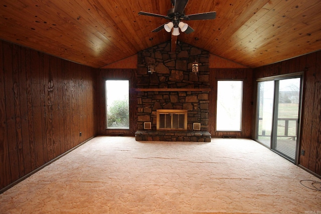 unfurnished living room featuring wood walls, a fireplace, and a wealth of natural light