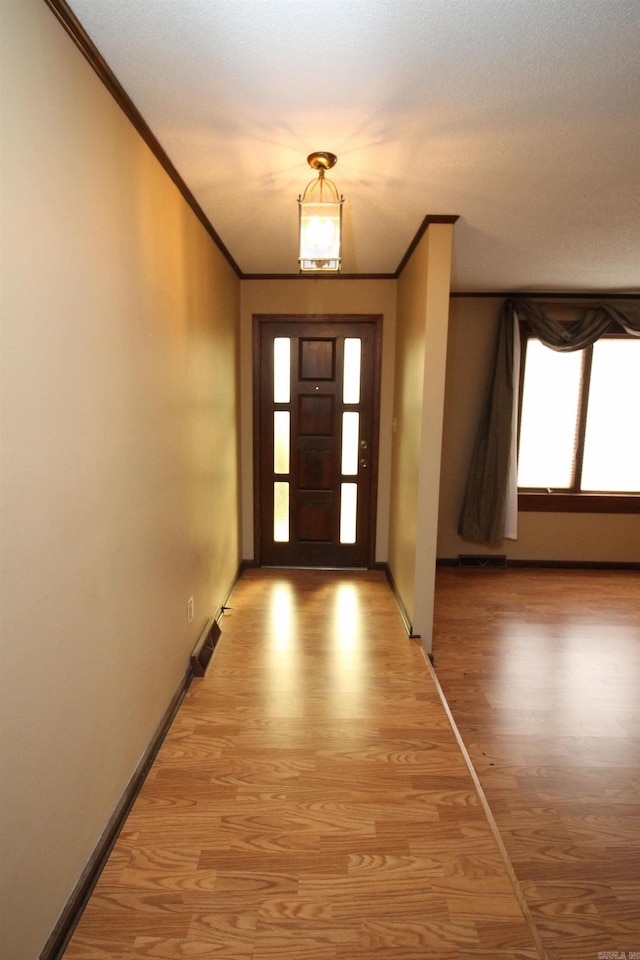 foyer entrance with wood-type flooring and crown molding