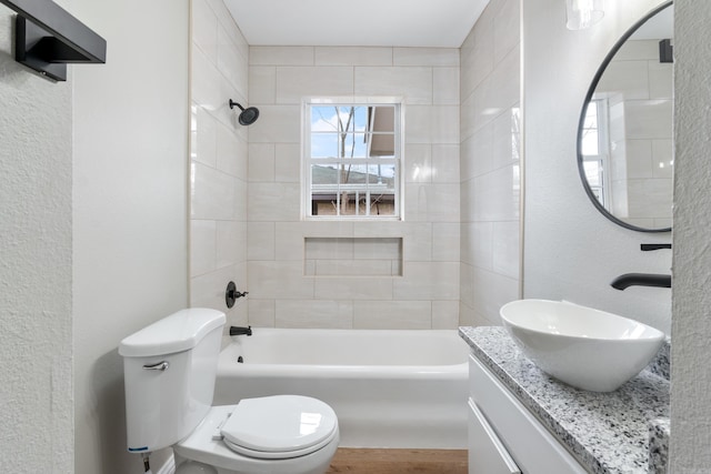 full bathroom with vanity, tiled shower / bath combo, and toilet