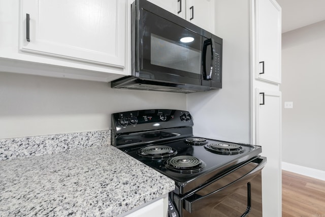 kitchen with light stone counters, white cabinetry, and black appliances