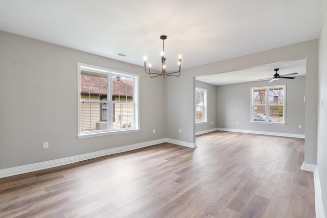 empty room featuring ceiling fan with notable chandelier and light hardwood / wood-style floors