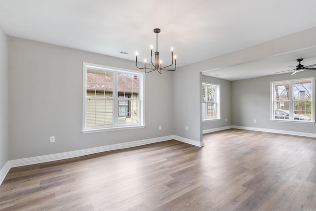 spare room with ceiling fan with notable chandelier and light hardwood / wood-style floors