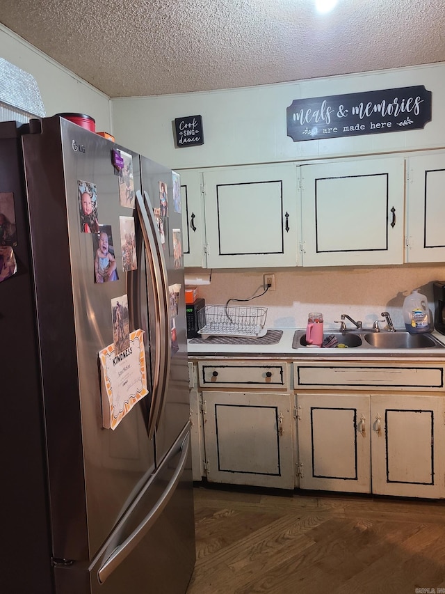 kitchen with stainless steel fridge, a textured ceiling, sink, dark hardwood / wood-style floors, and white cabinetry