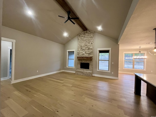 unfurnished living room featuring beam ceiling, a fireplace, hardwood / wood-style floors, and ceiling fan with notable chandelier