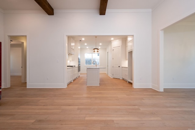 unfurnished living room featuring beam ceiling, sink, and light wood-type flooring