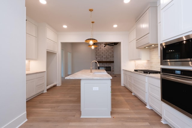 kitchen featuring white cabinetry, pendant lighting, and a center island with sink