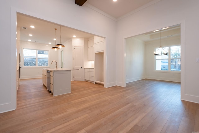 kitchen featuring white cabinetry, light hardwood / wood-style flooring, stainless steel dishwasher, pendant lighting, and a kitchen island with sink