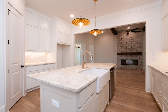 kitchen featuring sink, a center island with sink, white cabinets, and decorative light fixtures