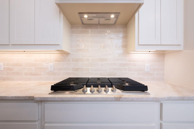 kitchen featuring tasteful backsplash, white cabinetry, stainless steel gas cooktop, and light stone counters