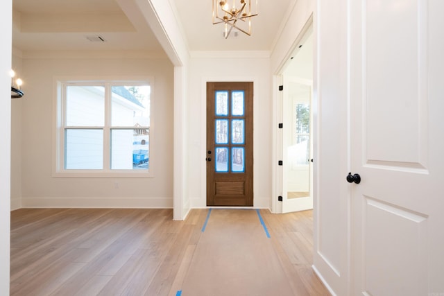 foyer featuring ornamental molding, light hardwood / wood-style floors, and a notable chandelier