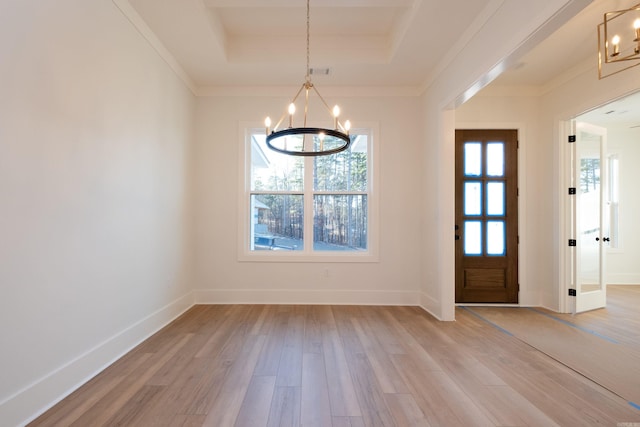 entrance foyer featuring a tray ceiling, ornamental molding, light hardwood / wood-style floors, and a chandelier