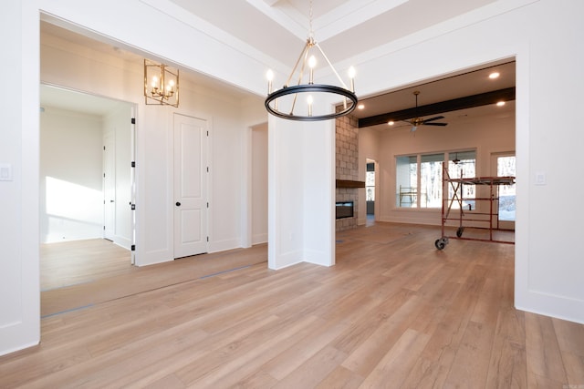 interior space featuring beamed ceiling, a large fireplace, ceiling fan with notable chandelier, and light wood-type flooring