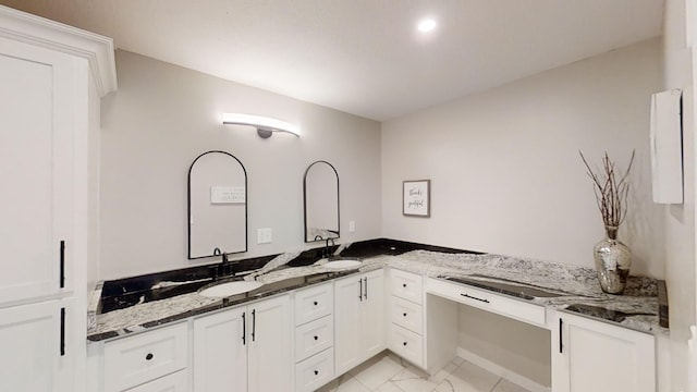 kitchen featuring white cabinets, kitchen peninsula, dark stone counters, and sink