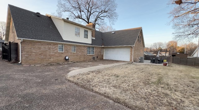 back of property with central AC unit and a garage