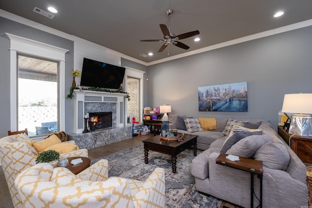 living room with hardwood / wood-style floors, ceiling fan, a fireplace, and crown molding