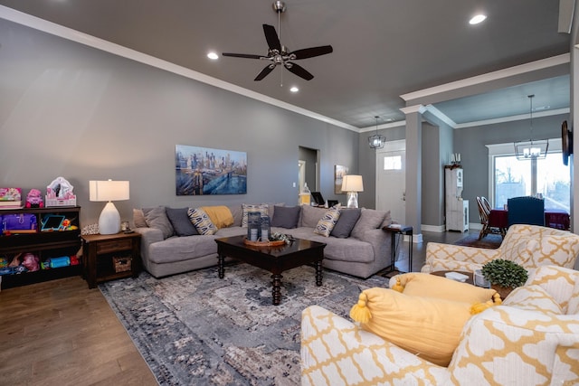 living room with wood-type flooring, ceiling fan with notable chandelier, and ornamental molding