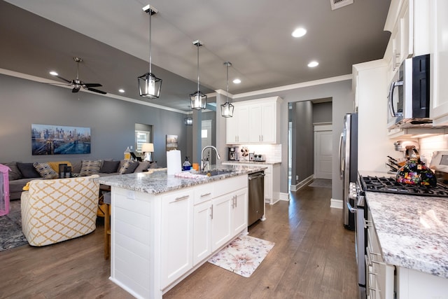 kitchen with backsplash, a center island with sink, white cabinets, and appliances with stainless steel finishes