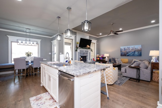 kitchen featuring white cabinets, a center island with sink, sink, stainless steel dishwasher, and decorative light fixtures