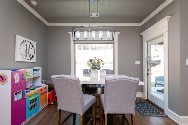 dining room with dark hardwood / wood-style floors, crown molding, and an inviting chandelier